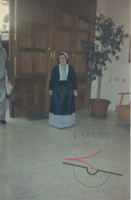 An elderly woman, possibly Gruppetta's mother wearing a costume for a party