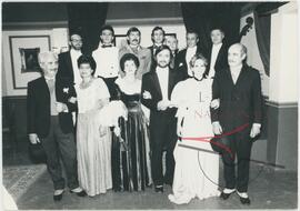 Grupetta with a group of men and women, wearing formalwear, acting on stage