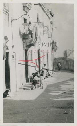 Women and children on doorsteps in a street in Cospicua