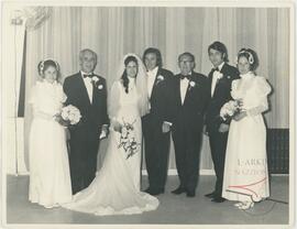 Karmenu posing with a bride and groom and other people for a wedding picture