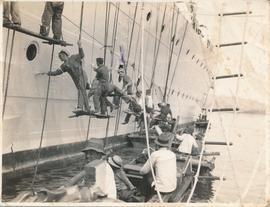 Sailors painting the side of a ship