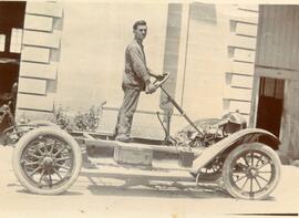 A person standing on an unbodied car chassis (see also image 059)