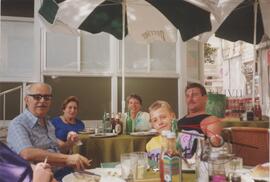 Karmenu, Guza, and two other people and a young boy sitting at tables