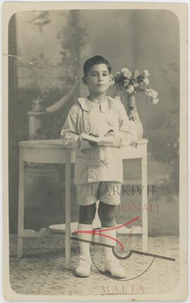 karmenu wearing a Holy Communion outfit posing for a picture in a photographic studio