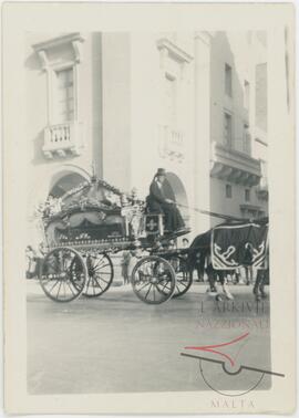 A horse-drawn cart carrying a coffin during a funeral procession