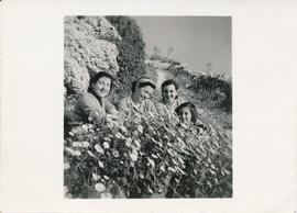 The Pizzuto sisters and a friend crouching in a flower bed