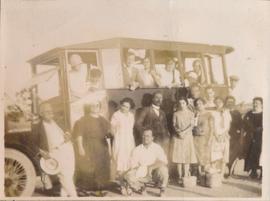 A group of people posing for a photograph alongside a bus