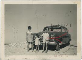 Children posing for a photo with a car